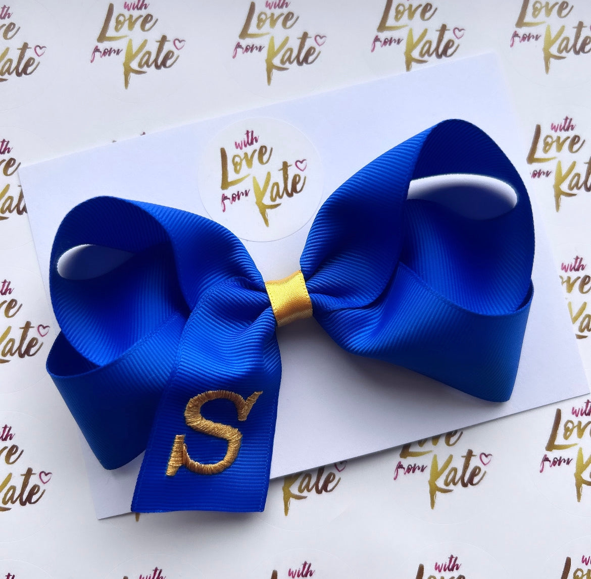 A royal blue boutique bow with yellow gold embroidery